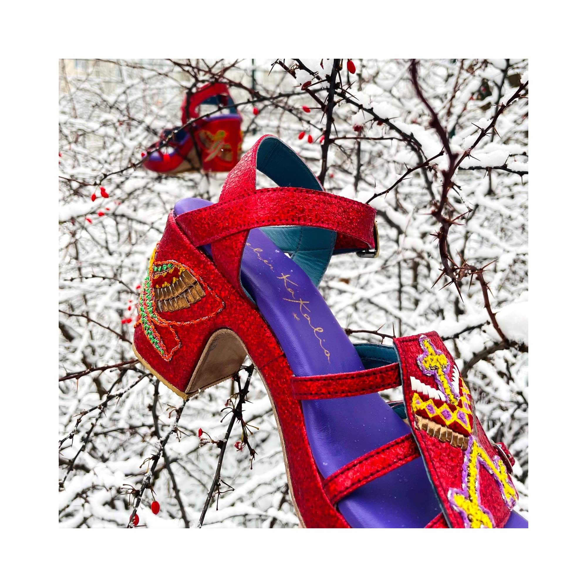 GOLD HOPPER splash poppy photographed against snowy branches, showing red leather straps and tribal embroidery