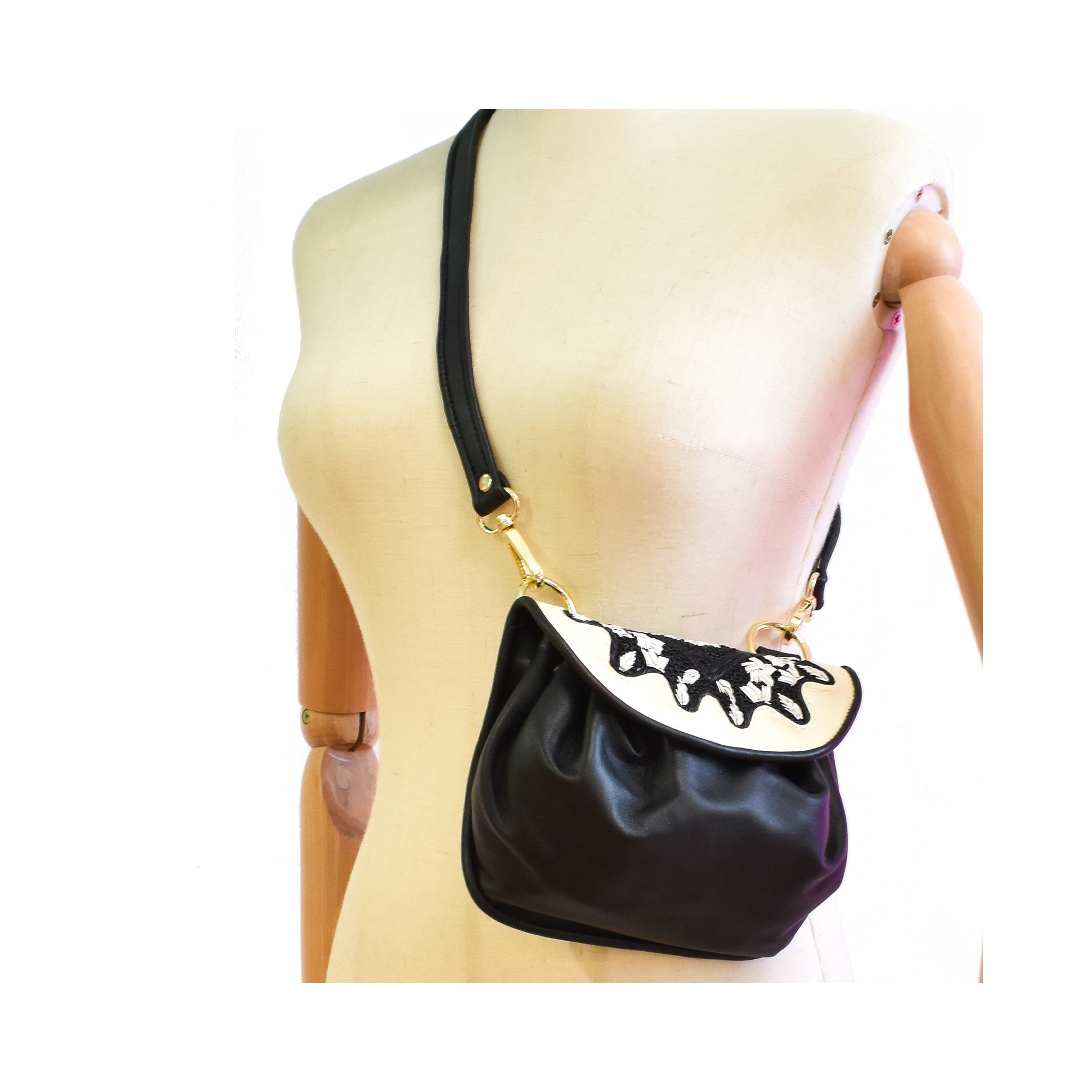 Black leather mini crossbody bag with white flap and black embroidery detail.